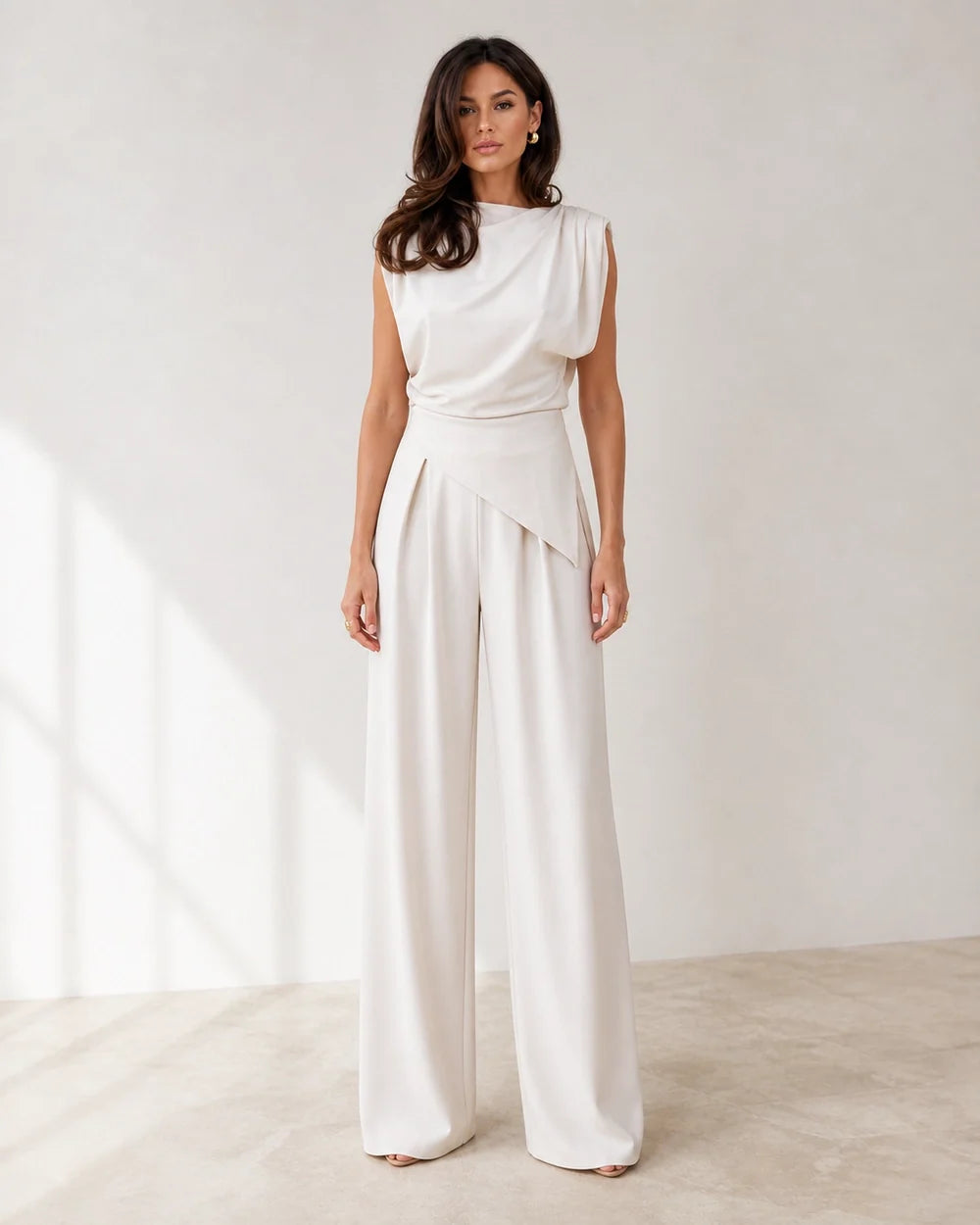 Women's white asymmetric draped top and wide-leg trousers set, full silhouette.