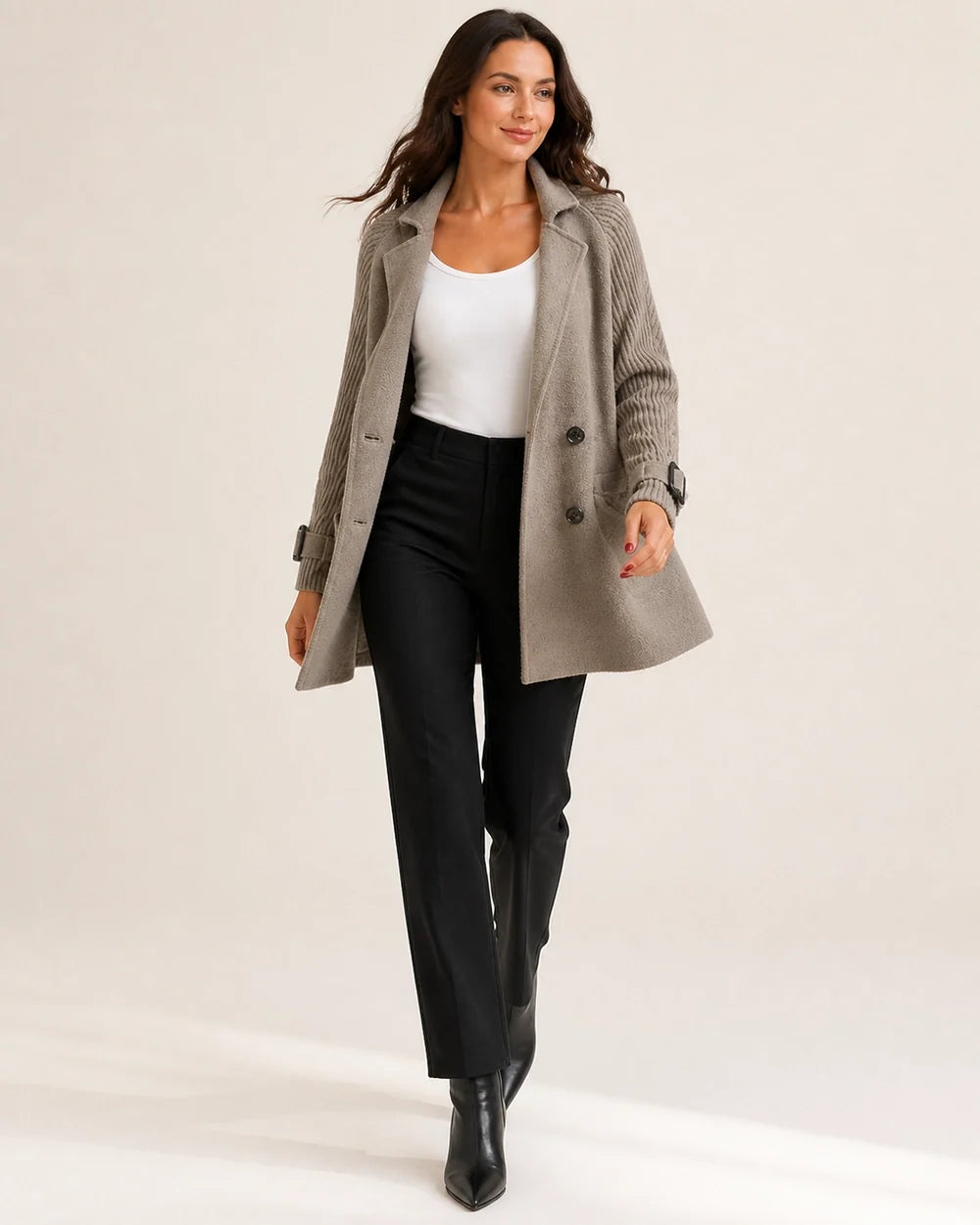 Taupe mid-length coat with knit sleeves worn in movement.