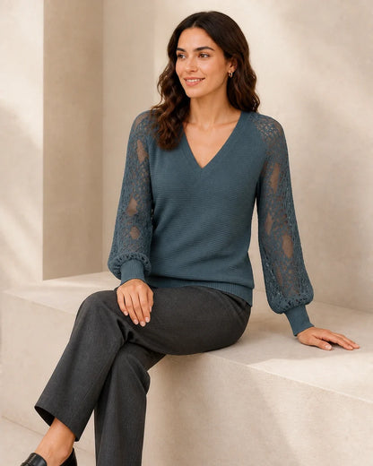 Women's Storm Blue ribbed V-neck sweater with floral lace sleeves, seated styling view.